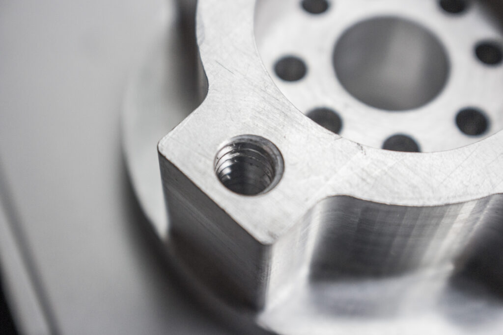 Close-up of a tapped threaded hole in a CNC-machined aluminum component.
