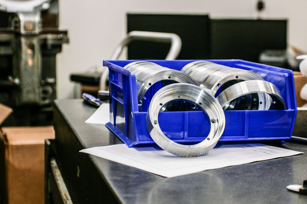 Precision-machined metal rings stored in a workshop bin for production assembly.