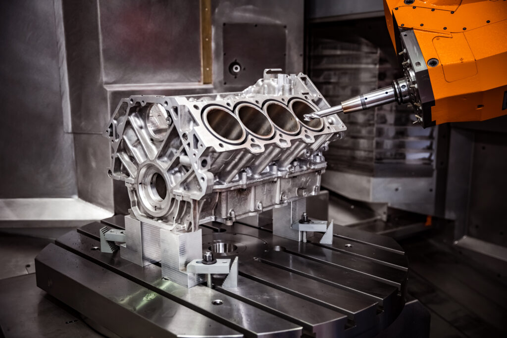Multi-axis CNC machining center machining an aluminum automotive engine block.