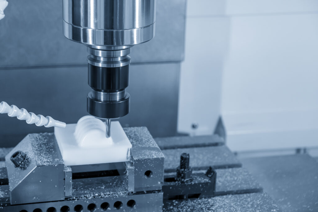 CNC milling process machining a white polymer component clamped in a precision vise.