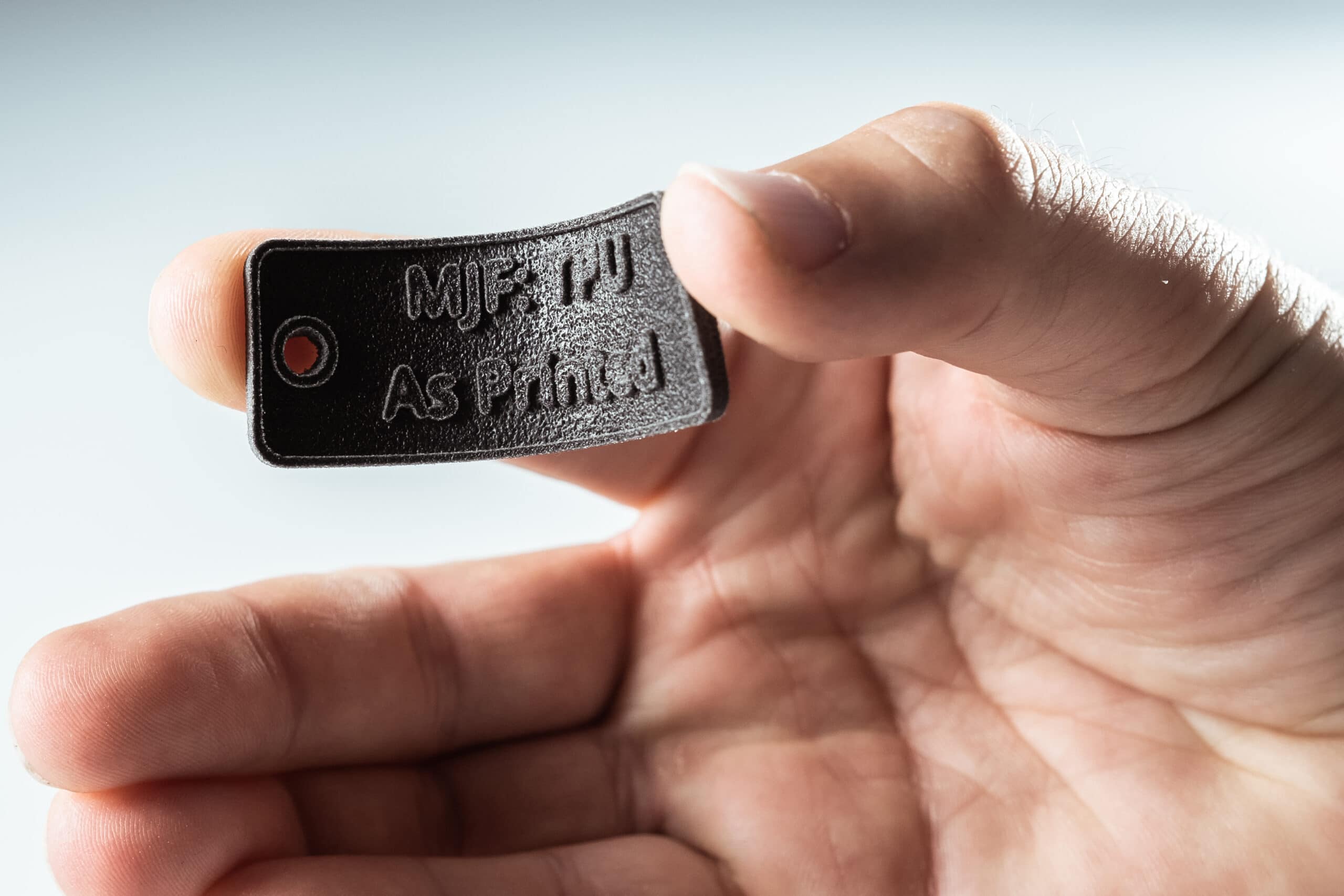 Hand holding a white flexible MJF 3D-printed TPU sample