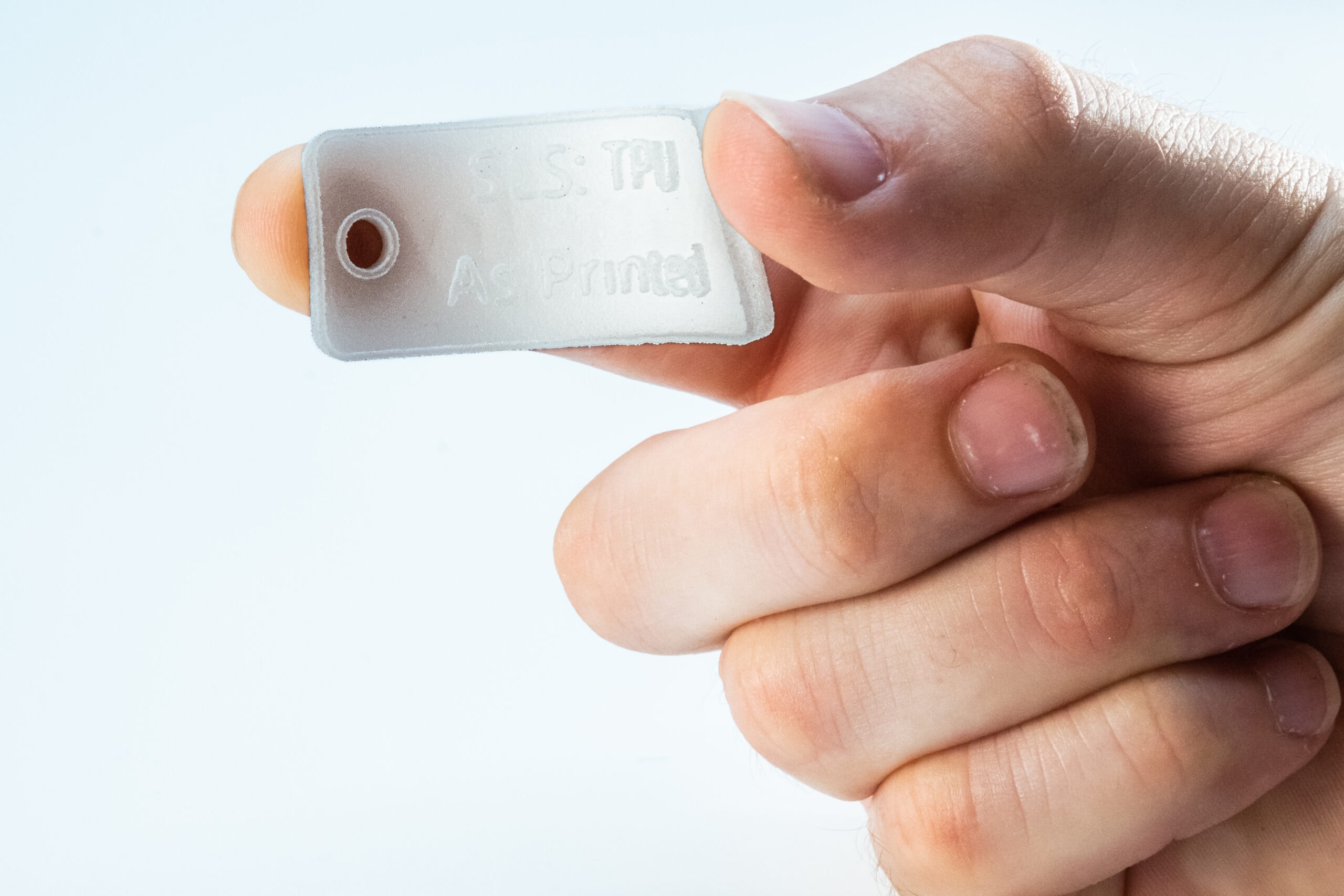 Hand holding a white flexible SLS 3D-printed TPU sample
