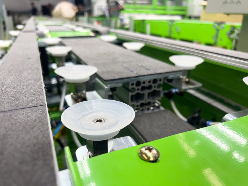 A section of an industrial assembly line focusing on green machinery equipped with suction cups.