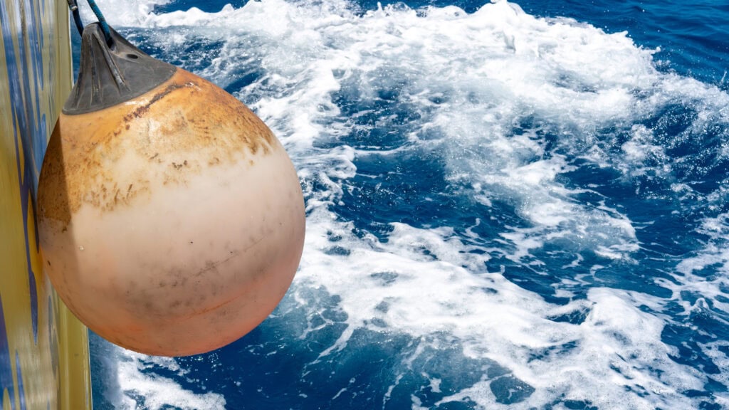 A bright orange HDPE navigation buoy that has undergone years of UV and environmental exposure