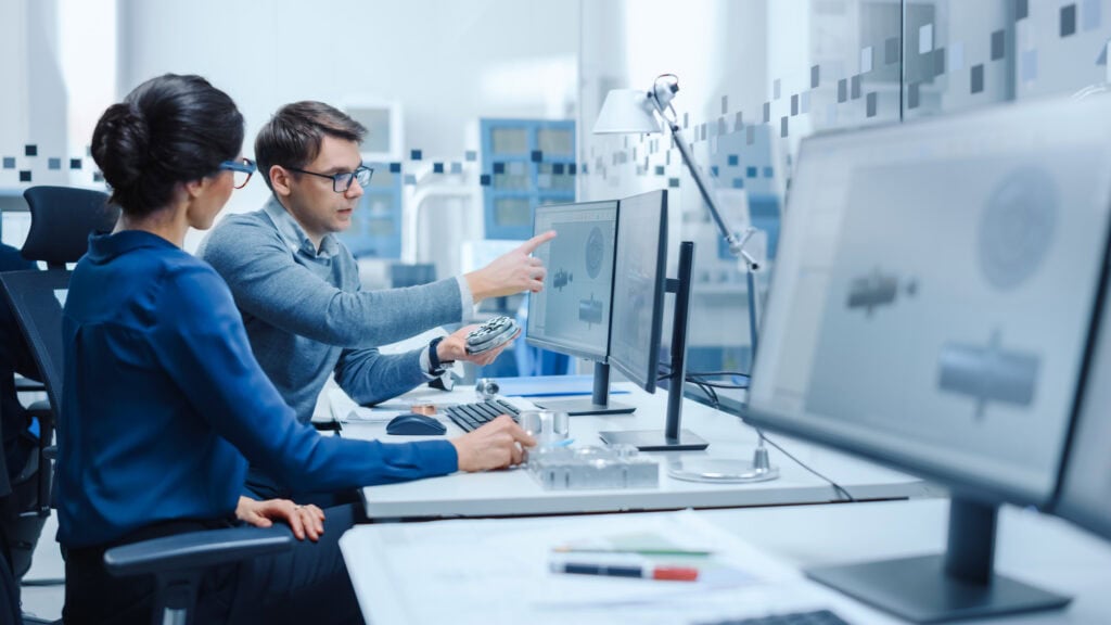 Engineers comparing a physical metal part to a digital CAD model during a DfM review.