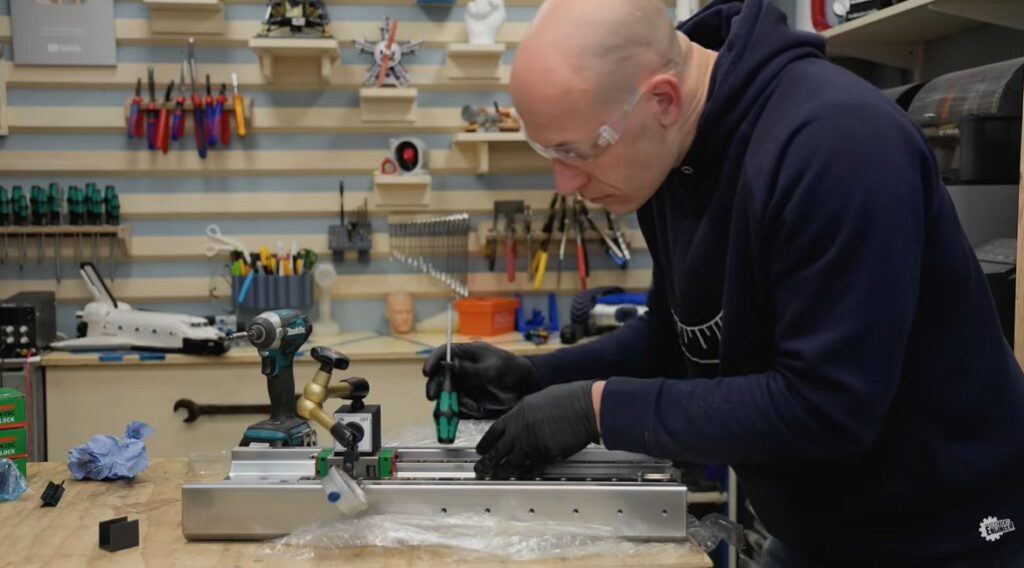 The Practical Engineer assembling the Z-axis linear rail system on a workshop bench during the 5-axis CNC build